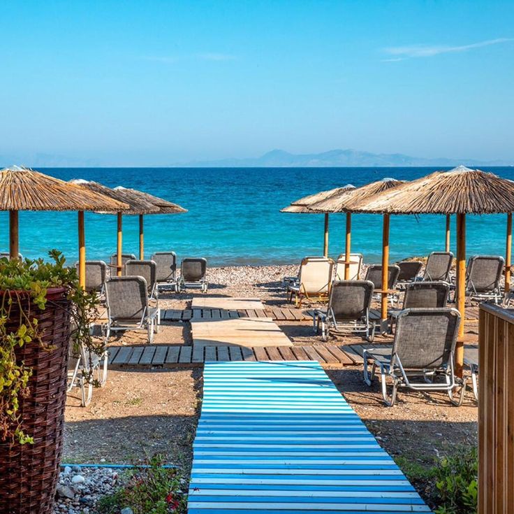 chairs and umbrellas are on the beach by the water