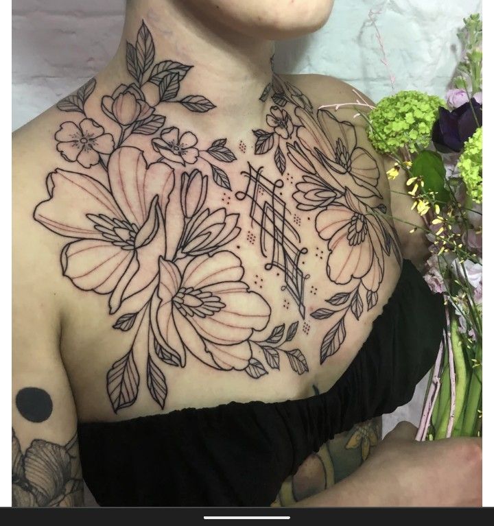 a woman with tattoos on her chest holding flowers