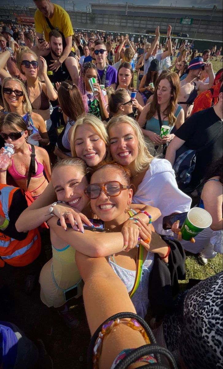 a group of young women hugging each other at a music festival