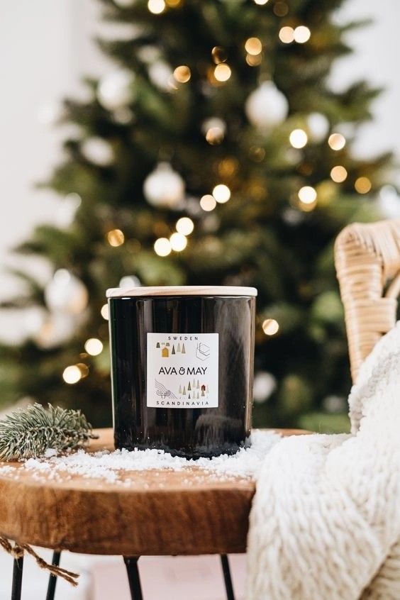 a candle sitting on top of a wooden table next to a christmas tree