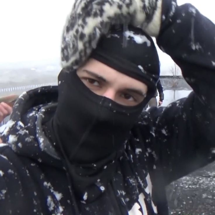 a man wearing a black and white hat covered in snow