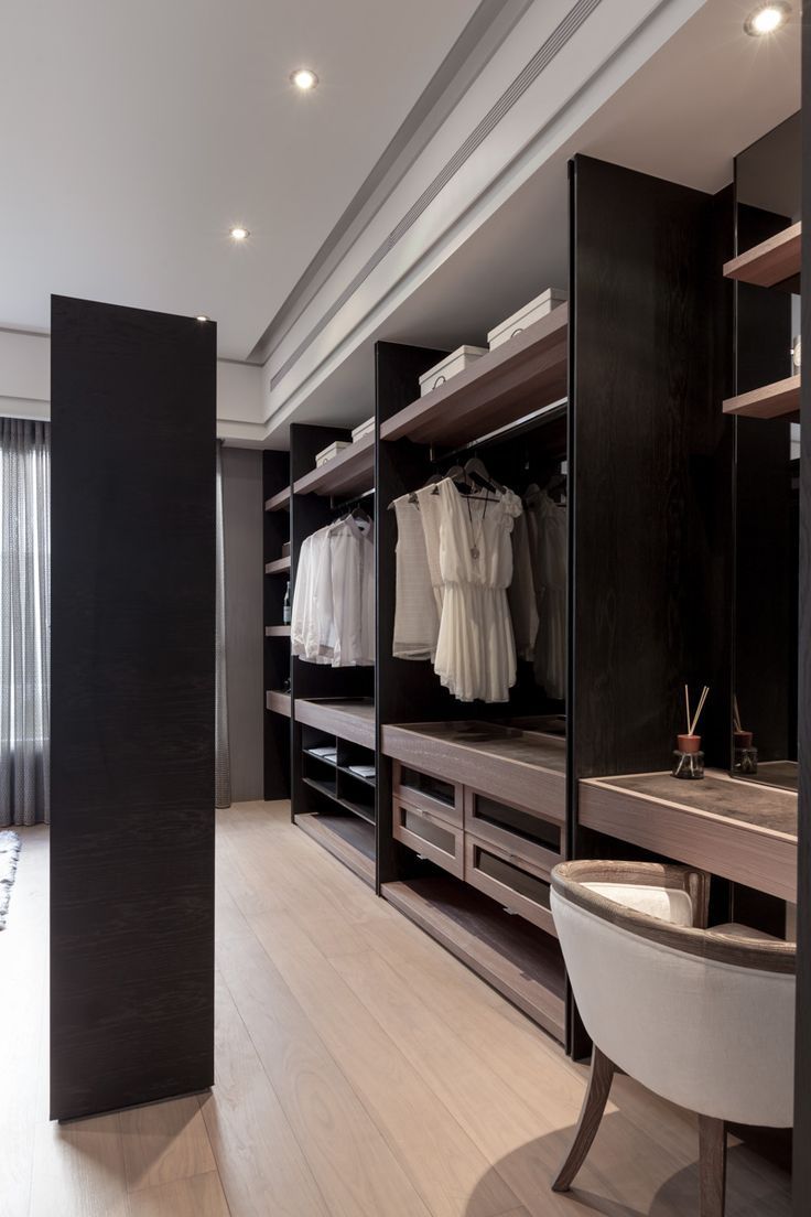 a large walk - in closet with lots of clothes on the shelves, and a sink