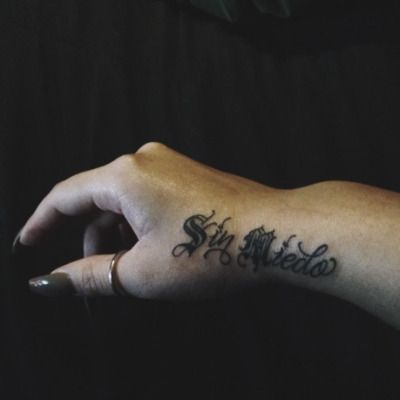 a person's hand with a tattoo on it and the word stay weird written in cursive writing