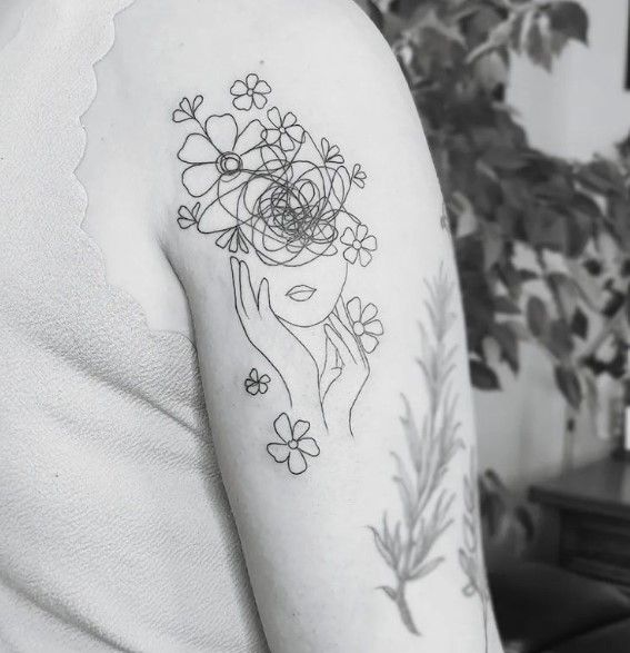 a black and white photo of a woman's arm with flowers on it