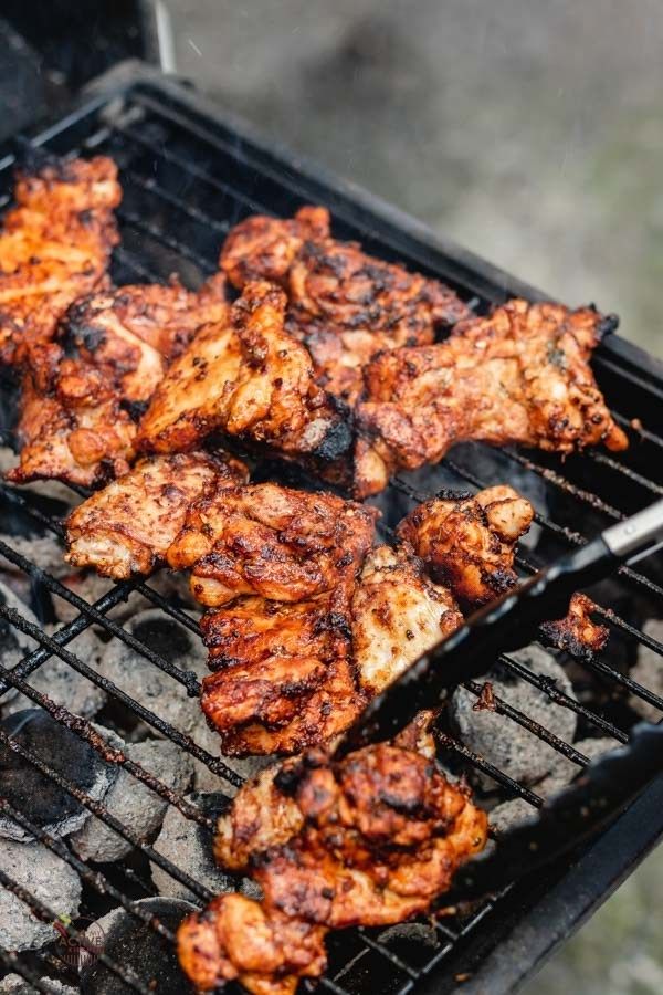 chicken is being cooked on the grill with tongs