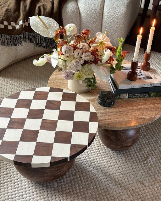 a checkered coffee table with flowers and candles in the background on a white rug