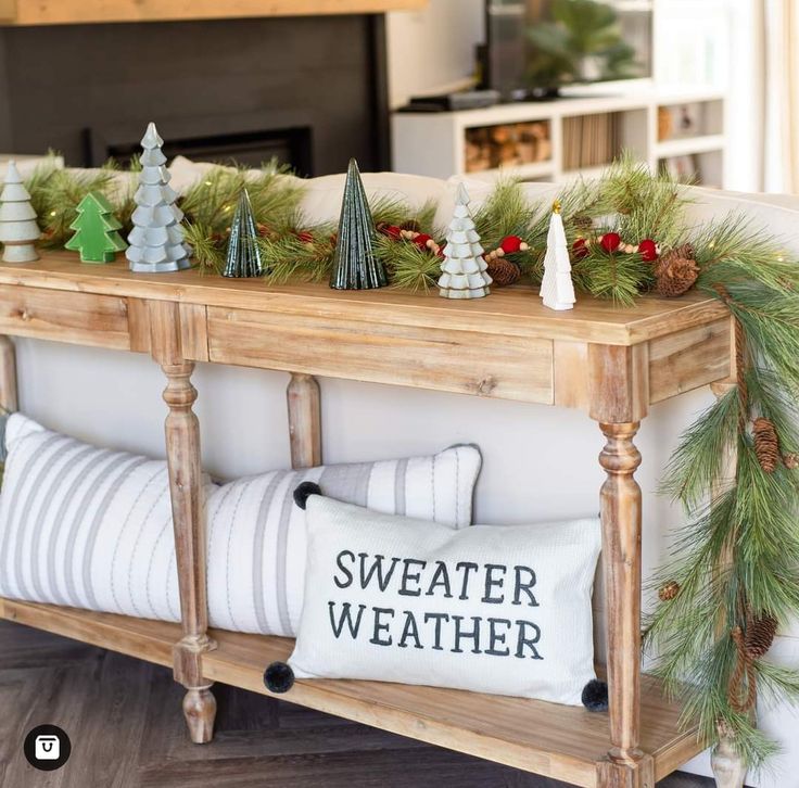 a couch with christmas decorations on it and a pillow that says sweater weather next to the couch