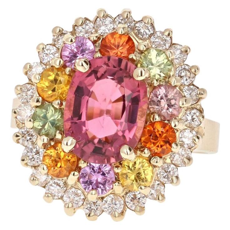 This ring has a 2.31 carat Oval Cut Pinkish-Mauve Tourmaline and is elegantly surrounded by 10 Round Cut Multi-Colored Sapphires that weigh 1.57 carats and further surrounded by 26 Round Cut Diamonds that weigh 0.65 carats. The total carat weight of this ring is 4.53 carats. This ring is curated in 14K Yellow Gold and weighs approximately 8.2 grams. This ring is a size 7 and can be re-sized at no additional charge. Simply a beautiful work of art to add to your jewelry collection! Yellow Gold Cocktail Ring, Sapphire Cocktail Ring, Pink Spinel, Fire Opal Ring, Multi Sapphire, Rainbow Jewelry, Gold Cocktail Ring, Gold Cocktail, Diamond Cocktail Rings