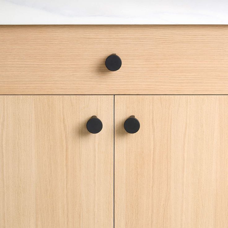 a cabinet with two black knobs on the front and one white button on the back