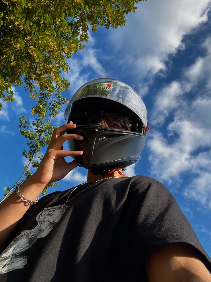 a person with a helmet on talking on a cell phone while wearing a motorcycle helmet