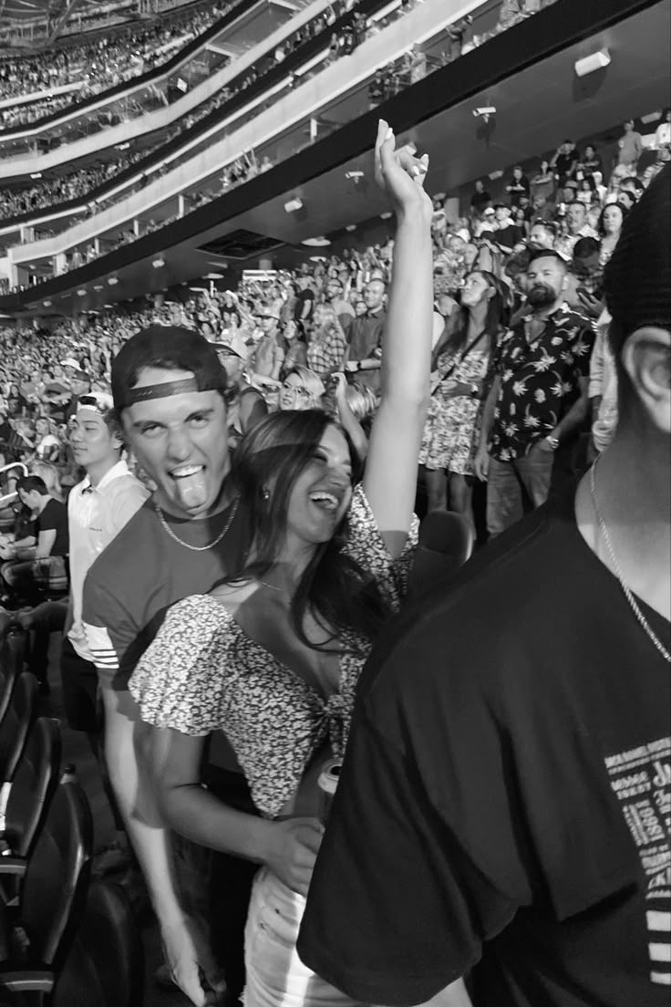 a group of people sitting in the stands at a baseball game with their hands up