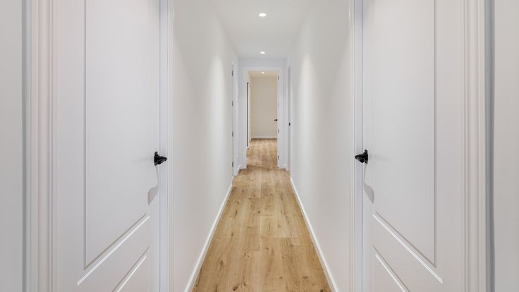 an empty hallway with white walls and wooden floors