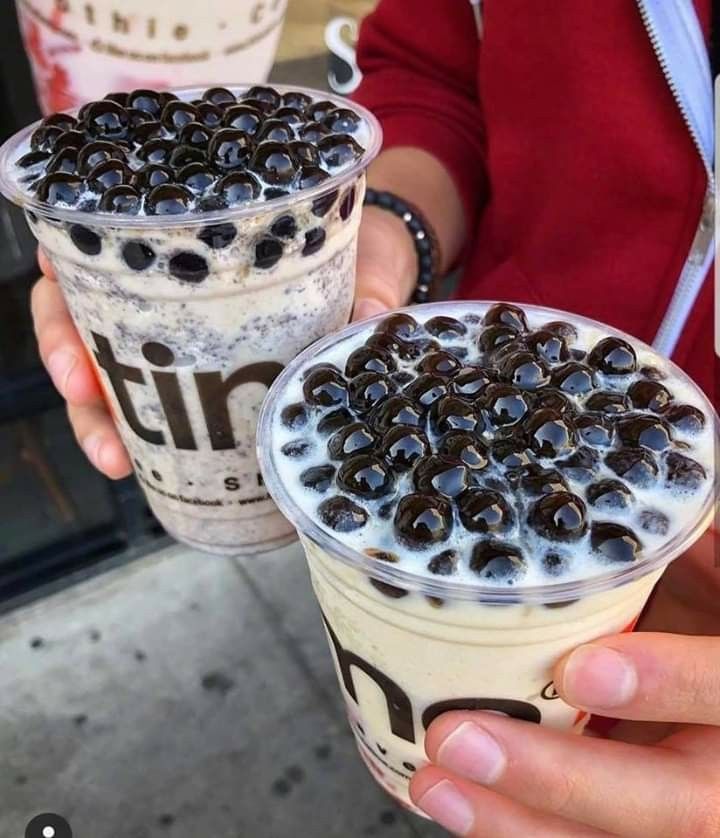 two people holding up drinks with black olives on top and ice cream in the middle