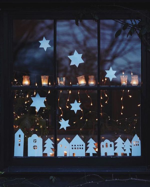 the window is decorated with white stars and lit candles