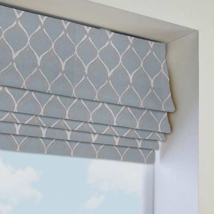 a window with a blue and white patterned roman blind in front of the windowsill