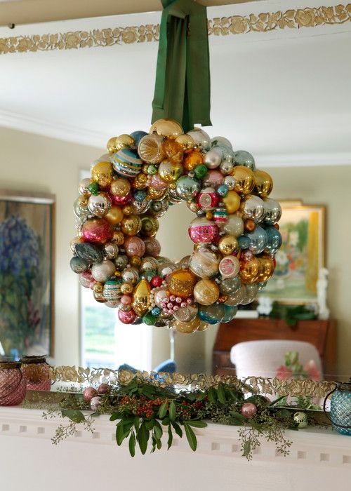 a christmas wreath hanging from the ceiling in front of a mantel with ornaments on it