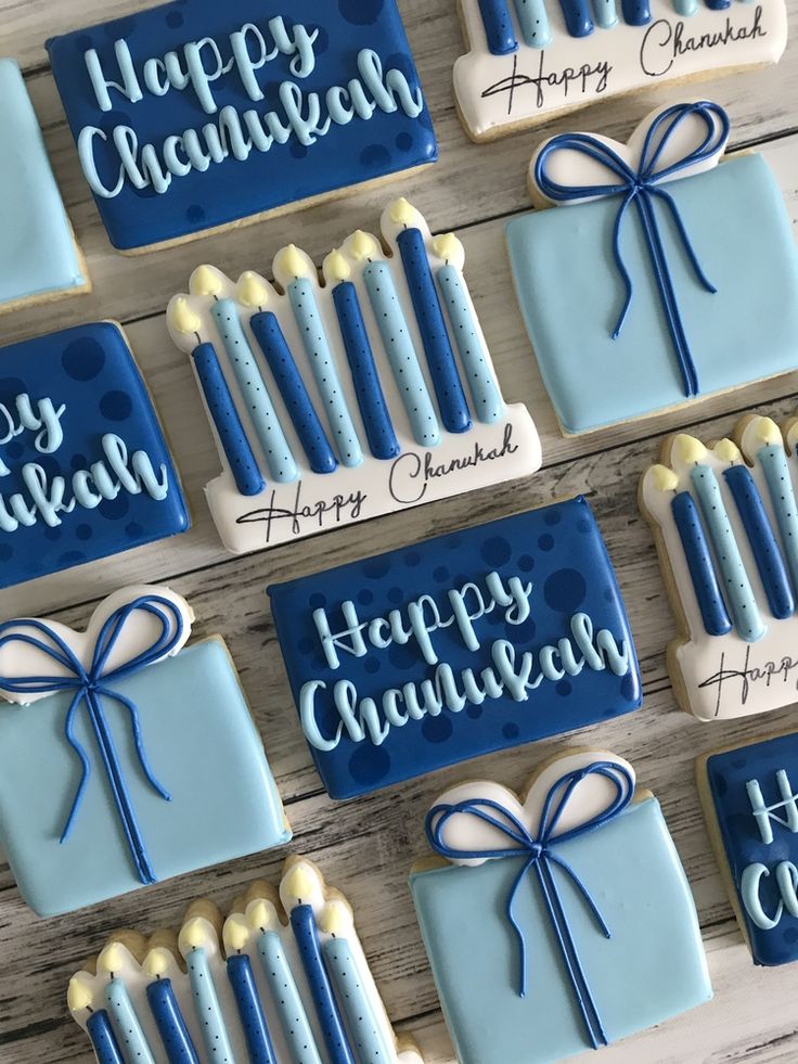 decorated cookies with candles and happy hanukkah written in blue icing on a wooden table