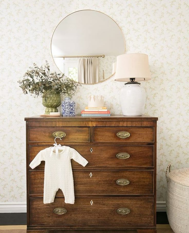 a dresser with a mirror and baby's clothes on it