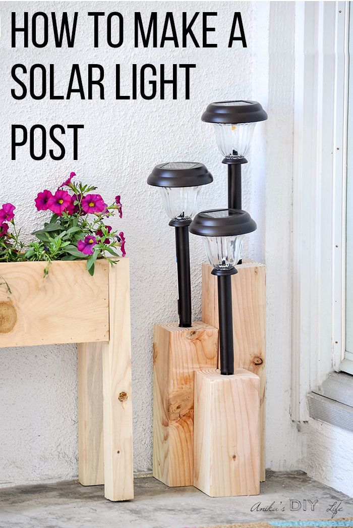 three solar lights sitting next to each other on top of a wooden box with flowers in it