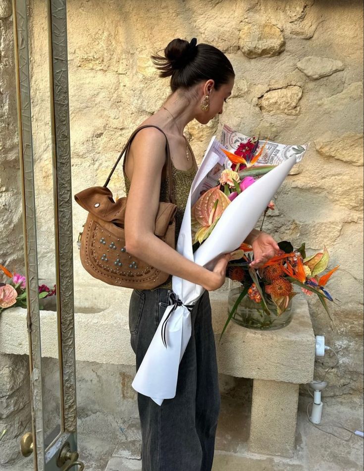 a woman is holding flowers in her hand and looking at the paper she has placed on her shoulder