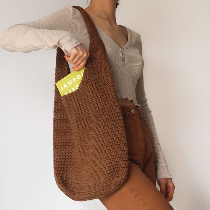 a woman holding a brown bag with a yellow tag on it's side and her right hand in the pocket