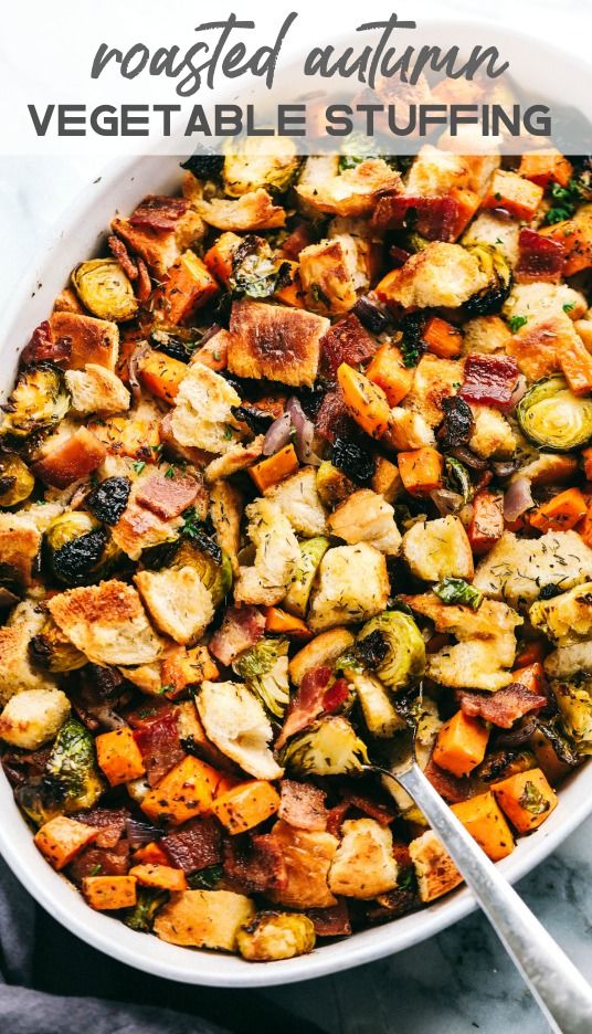 a white bowl filled with roasted vegetables and topped with a serving spoon next to a gray napkin