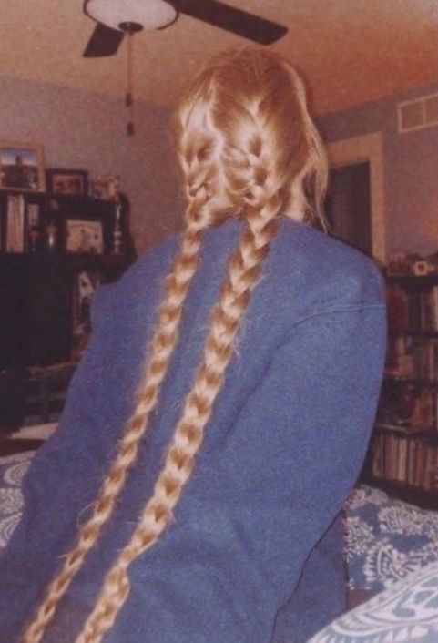 a woman with long blonde hair sitting on top of a bed next to a ceiling fan