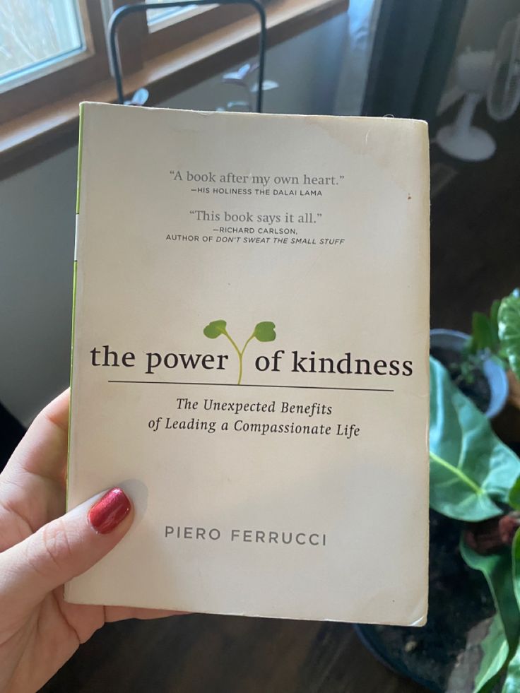 a person holding up a book about the power of kindness