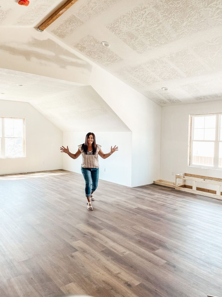 a woman is running in an empty room with her arms spread out and hands outstretched