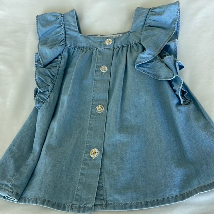 Chambray Girls Shirt With Daisy Buttons. Brand New With Tags And Never Worn Or Used. Soft And 100% Cotton. Size 2-3 Years Ruffled Tops For Playdate In Summer, Blue Short Sleeve Top For Playdate, Summer Cotton Top For Playdate, Cute Denim Top For Spring, Cotton Ruffle Tops For Playdate, Cute Ruffled Tops For Playwear, Cute Casual Cotton Tops, Cute Blue Tops For Playdate, Cute Blue Denim Tops