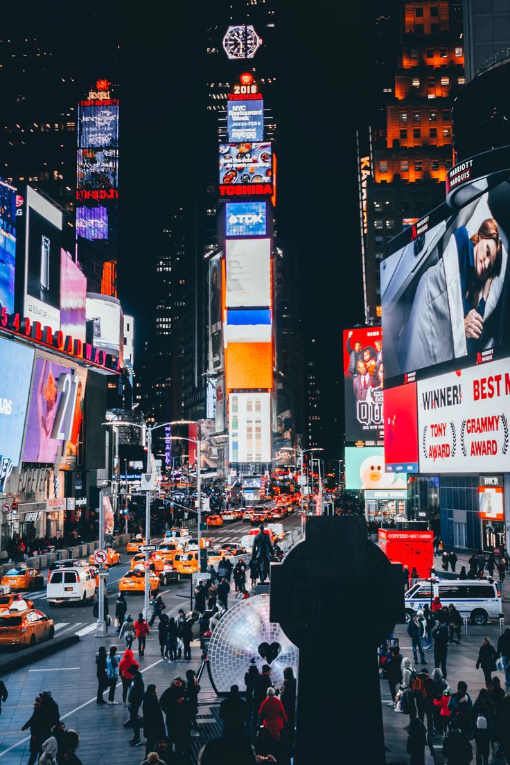 a busy city street filled with lots of traffic and tall buildings at night in new york