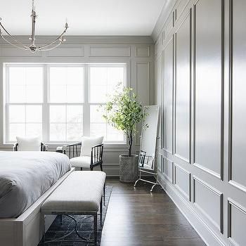 a bedroom with white walls and wood flooring has a large bed in the middle