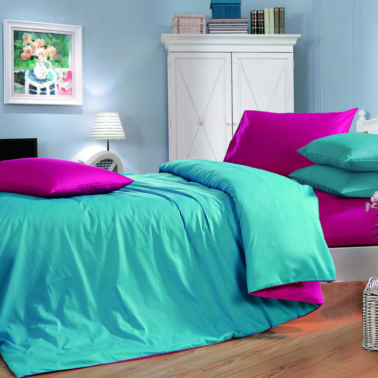 a bed with blue and pink sheets in a room