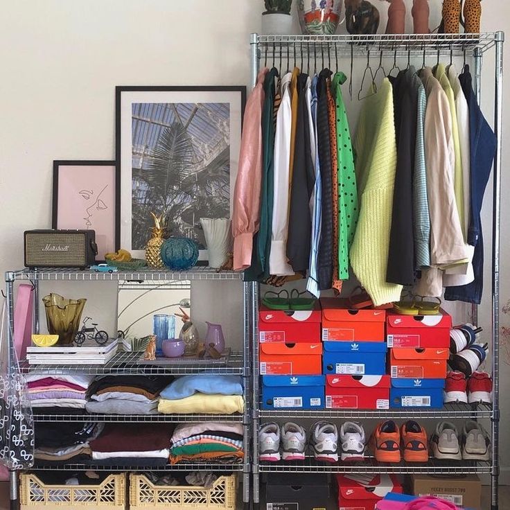 an organized closet with clothes, shoes and other items on shelves in front of a wall