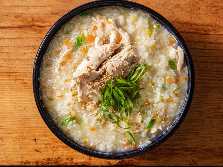 a bowl filled with rice and meat on top of a wooden table