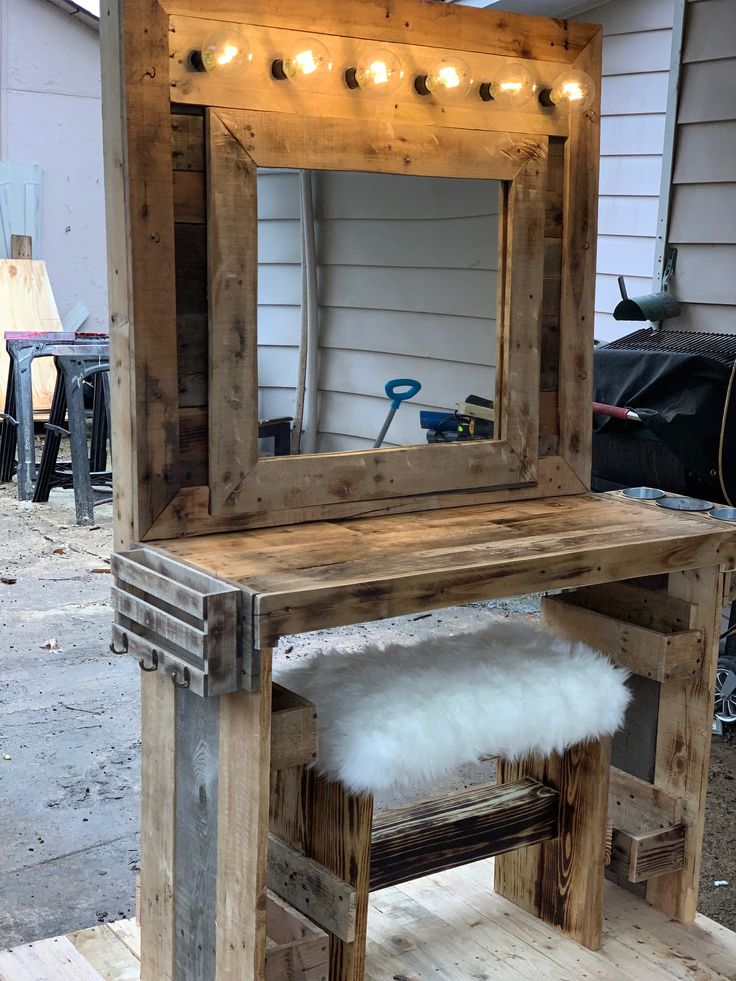 a vanity made out of pallet wood with lights on the mirror and bench underneath