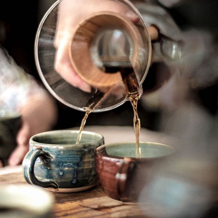 a person pouring coffee into two cups