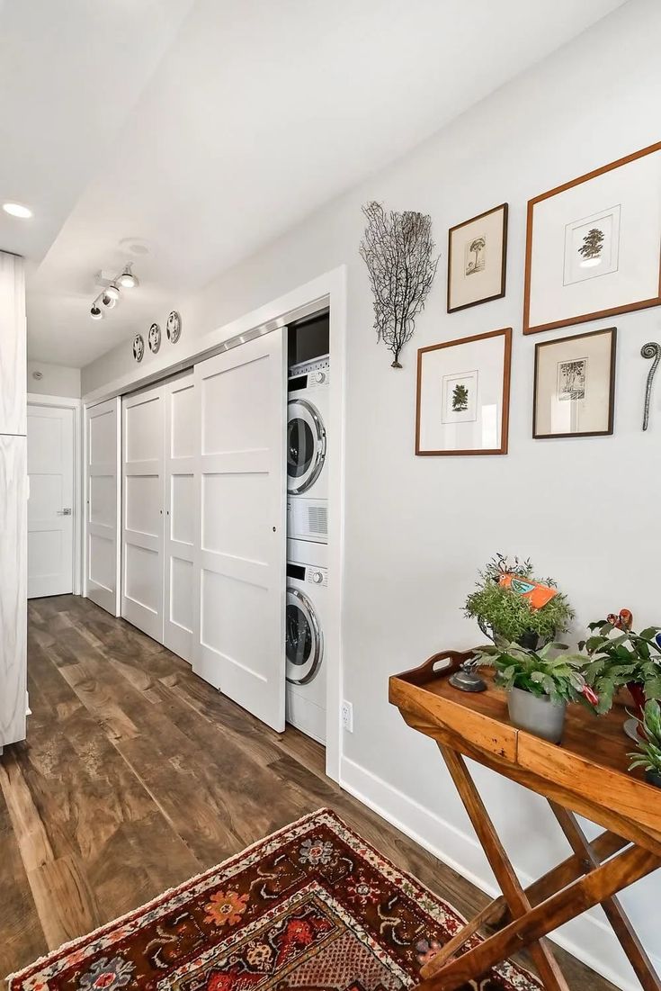 a washer and dryer sitting in a room next to a table with flowers on it