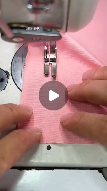 two hands are using a sewing machine to sew on pink material that has been stitched together