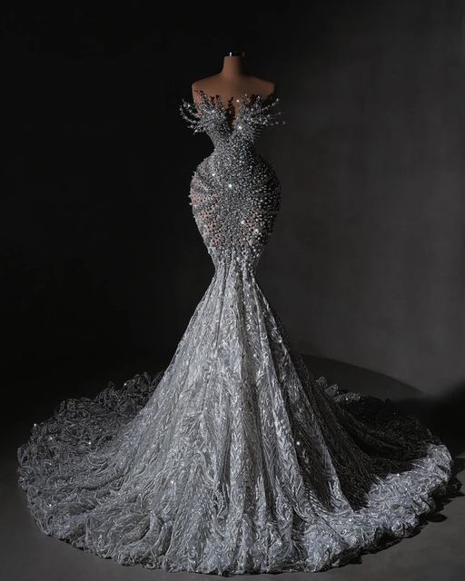 the back of a silver dress with sequins on it, in front of a black background