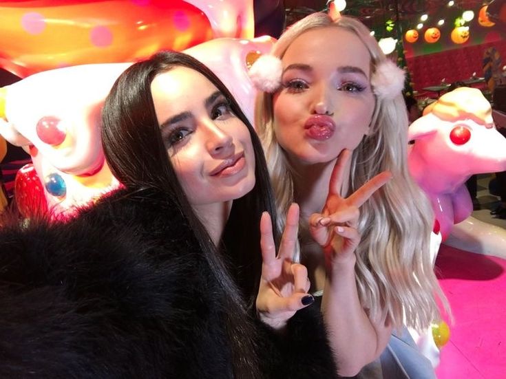 two beautiful young women standing next to each other making the peace sign with their fingers