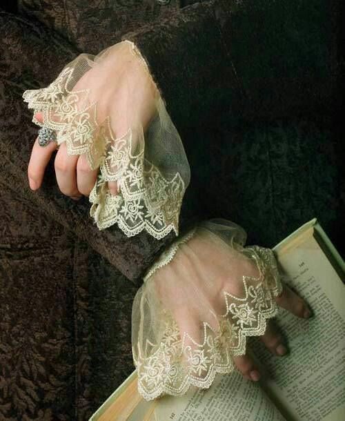 two hands with lace on them are holding an open book