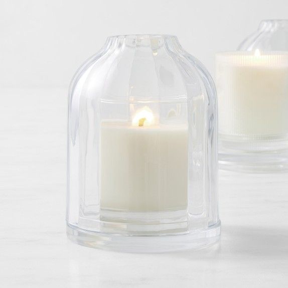 two clear glass candle holders sitting on top of a white counter next to each other