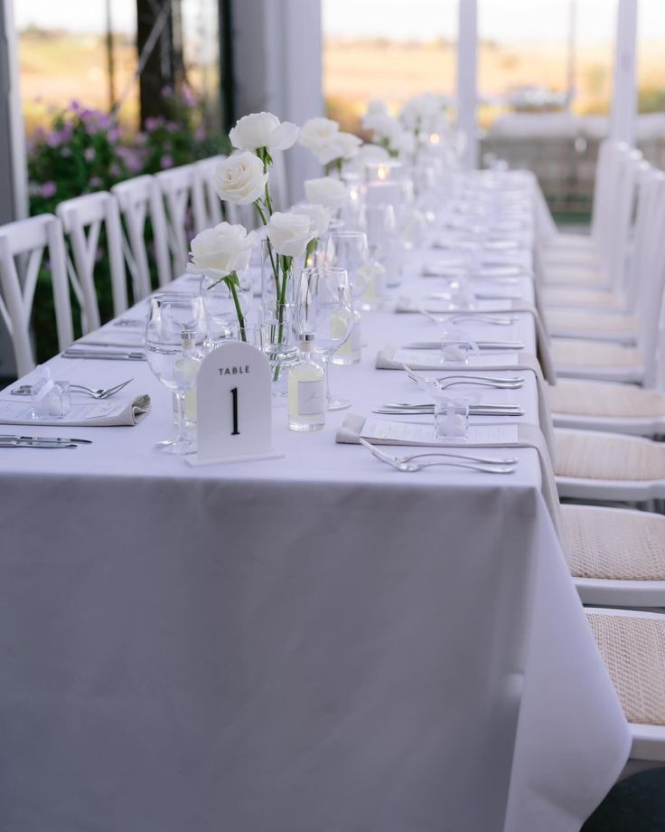 a long table with white flowers and place settings