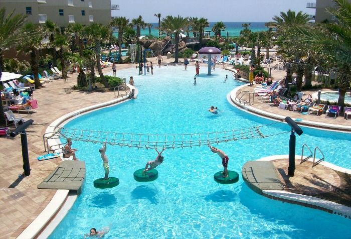 people are swimming in an outdoor pool near the beach