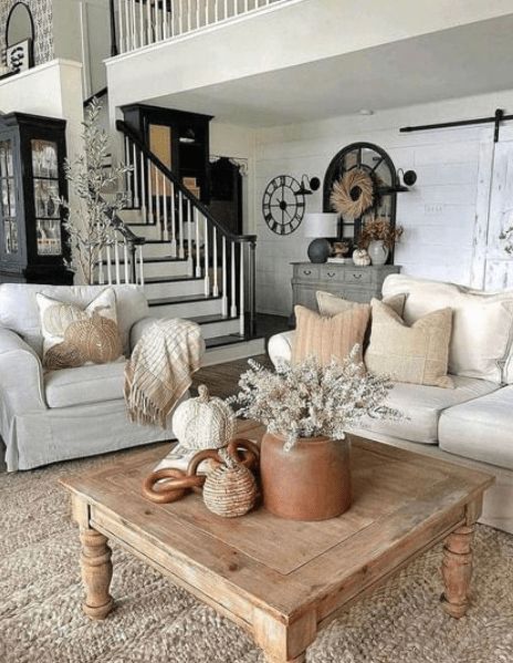 a living room filled with furniture and a wooden table in front of a stair case