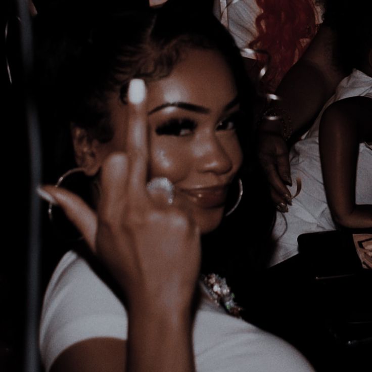 a woman sitting in a car with her hand up to the camera, making a peace sign