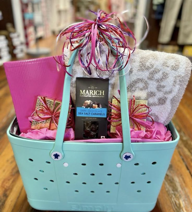 a blue basket filled with lots of different types of items and wrapped in pink ribbon