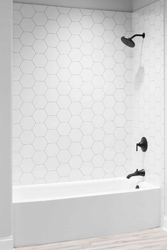 an empty bathroom with white tile and black faucet shower head in the corner