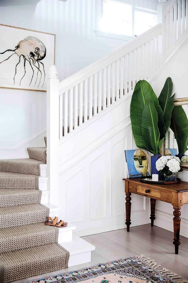 there is a plant on the table in front of the stair case and some pictures